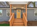 A welcoming covered front porch with a yellow front door and newly stained wood stairs at 4179 Hanes Dr, Decatur, GA 30035