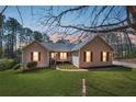 Charming ranch-style home with a well-manicured lawn, inviting curb appeal, and a cozy front porch at dusk at 100 Cowan Trl, Stockbridge, GA 30281