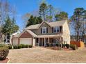 Well-maintained two-story home showcasing a three-car garage, lush landscaping, and a welcoming front porch with red accents at 2702 Brookefield Nw Ln, Kennesaw, GA 30152