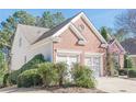 Angle view showing the side of a brick home, highlighting the two-car garage and mature landscaping at 5226 Davis Love Dr, Cumming, GA 30041