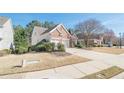 View of a brick home's driveway, showcasing the two-car garage, landscaping, and sidewalk at 5226 Davis Love Dr, Cumming, GA 30041