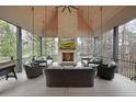 Inviting covered patio with a stone fireplace, comfortable seating, and a mounted TV, perfect for outdoor relaxation and entertainment at 1025 Abingdon Ln, Johns Creek, GA 30022