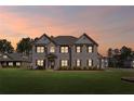 Beautiful two-story home with a gray brick facade set against a picturesque sunset backdrop at 701 Cupcake Ct, Mcdonough, GA 30252