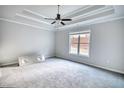 Spacious bedroom with a tray ceiling, large window and neutral carpet at 690 Park Place Way, Social Circle, GA 30025
