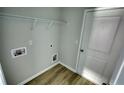 Well-lit laundry room with wood-look floors and access to utilities at 690 Park Place Way, Social Circle, GA 30025
