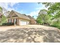 Long driveway and three-car garage, surrounded by lush greenery and mature trees in a serene setting at 8155 Legends View Ct, Cumming, GA 30028