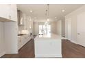 Open kitchen with white cabinets, stainless steel appliances, a large island, and hardwood floors at 161 Basil St, Cumming, GA 30040