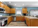 U-shaped kitchen featuring wood cabinets, stainless steel appliances, and modern flooring at 4695 Ferncrest Pl, Douglasville, GA 30135