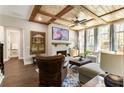 Cozy living room with wood-beamed ceiling, brick fireplace, and large windows showcasing outdoor views at 3560 Chattahoochee Rd, Cumming, GA 30041