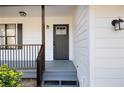 Inviting front porch with gray painted wood, black railing, and a charming entry door at 6730 Alvan Ct, Riverdale, GA 30296