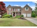 Charming two-story brick home featuring a well-manicured lawn and a two-car garage at 179 Bradshaw Park Dr, Woodstock, GA 30188