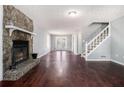 Spacious living room featuring a stone fireplace, wood floors, and staircase to the second floor at 570 Knollwood Dr, Stockbridge, GA 30281