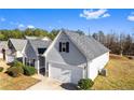 View of a well-maintained home with light gray siding, a dark roof, an attached garage, and a neatly landscaped lawn at 165 Birch St, Hiram, GA 30141