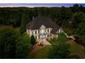 Aerial dusk view of house surrounded by tall trees; inviting landscape lighting at 19 Troup Ct, Acworth, GA 30101
