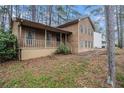 Exterior view of two-story home with a welcoming front porch and natural wood siding, nestled in a wooded lot at 444 Wellington Way, Jonesboro, GA 30238