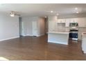 Open-concept living space flows to the kitchen featuring hardwood floors, island, and stainless appliances at 871 Pineberry Ct, Grayson, GA 30017