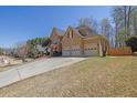 Side view of two-story home featuring a three-car garage, stone accents, and an expansive driveway at 1621 Telfair Chase Way, Lawrenceville, GA 30043