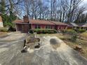 Front view of a home with brick accents, mature shrubbery, and a sprawling driveway at 1404 Aniwaka Sw Ave, Atlanta, GA 30311