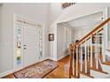 Bright foyer featuring hardwood floors and a classic staircase, adjacent to a sunlit living area at 1775 Unity Loop, Cumming, GA 30040