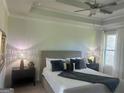 Inviting main bedroom with a tray ceiling, ceiling fan, stylish décor, and a bright window at 939 Park Place St, Social Circle, GA 30025