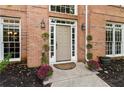 Close-up of front door with sidelights, potted flowers, and brick exterior, creating a warm entrance at 3851 Westwick Nw Way, Kennesaw, GA 30152