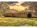 Sunset view of sprawling ranch-style home with a lush green lawn and mature trees at 5190 Paul Sw Cir, Conyers, GA 30094