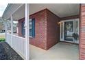 Close-up of a cozy, covered front porch with brick detailing, decorative shutters, and a charming entrance at 732 Jacoby Dr, Loganville, GA 30052