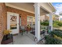 Charming front porch with brick facade, welcome decor, and seating area at 230 Rosenwald Ln, Hampton, GA 30228