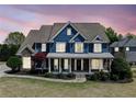 Charming two-story home with a covered front porch, manicured lawn and beautiful front yard landscaping at twilight at 302 Meadow Lark Xing, Canton, GA 30114