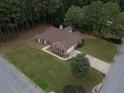Aerial view of a red brick home with an attached garage, a large yard, and mature trees at 3020 Templeton Ln, Loganville, GA 30052