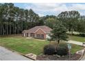 Red brick home with manicured lawn, mature trees, and a neighborhood street view at 3020 Templeton Ln, Loganville, GA 30052