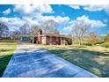 A quaint brick home featuring a covered carport and a well-maintained driveway under a bright, partly cloudy sky at 1715 Highway 11 N, Social Circle, GA 30025