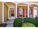 Inviting covered front porch with brick accents, white columns, and trimmed shrubbery at 303 Dexter Dr, Woodstock, GA 30188