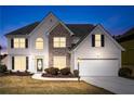 Charming two-story home at twilight featuring stone accents, a manicured lawn, and an attached two-car garage at 2373 Shady Maple Ln, Loganville, GA 30052