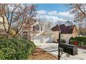 View of a two-story house with a two-car garage, set against a backdrop of mature trees and blue skies at 1056 Shady Valley Ne Pl, Brookhaven, GA 30324