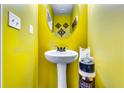 Bright half bathroom featuring yellow walls, a pedestal sink, and a round mirror at 1709 Creel Ln, Atlanta, GA 30349