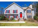 Beautiful two-story home with gray stucco, red shutters, stone accents, and a vibrant red front door at 4638 Arrow Wind Dr, Powder Springs, GA 30127