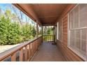 Covered porch featuring stained wood floors, rails, and trim, and view of the front yard trees at 4800 Timber Ridge Dr, Douglasville, GA 30135