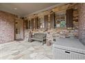 Covered patio with stone flooring, brick walls, and stylish outdoor seating at 13142 Overlook Pass, Roswell, GA 30075
