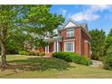 Side view of the red brick home showing landscaping, a well-manicured lawn, and a glimpse of the driveway at 711 Wilhaven Ct, Loganville, GA 30052
