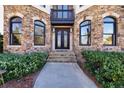 Elegant stone home with a striking front entrance featuring a decorative wrought iron door and manicured landscaping at 3491 Falls Branch Ct, Buford, GA 30519
