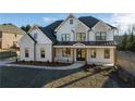 Elegant two-story home features white brick, black trim, and a covered porch, enhancing curb appeal at 4281 Sierra Creek Ct, Hoschton, GA 30548