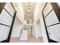 Grand foyer features soaring ceilings, a modern chandelier, and an open staircase with wood treads at 4281 Sierra Creek Ct, Hoschton, GA 30548