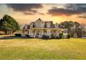 Charming two-story home with a spacious porch and well-manicured lawn with the sun setting at 2002 Orchard Terrace, Loganville, GA 30052