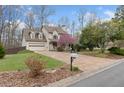 View of home's front lawn, blooming tree, two-car garage, driveway, and mailbox at 7810 Rose Ct, Cumming, GA 30040