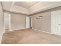 Large main bedroom with tray ceiling, neutral carpet, and multiple doors for added space and convenience at 5080 Galleon Xing, Decatur, GA 30035