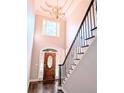 Bright foyer with a decorative chandelier, hardwood floors, and a staircase with a black railing at 3655 Brisbane Dr, Marietta, GA 30062