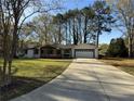 A ranch-style home with a long driveway, covered porch, and a two-car garage surrounded by mature trees at 3533 Johns Rd, Tucker, GA 30084