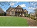 Charming two-story home with brick and stone facade, inviting front porch, and a lush green lawn at 7740 Nesbit Ferry Rd, Atlanta, GA 30350
