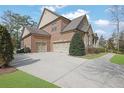 Spacious three-car garage and brick exterior with a well-maintained lawn and mature landscaping at 7740 Nesbit Ferry Rd, Atlanta, GA 30350